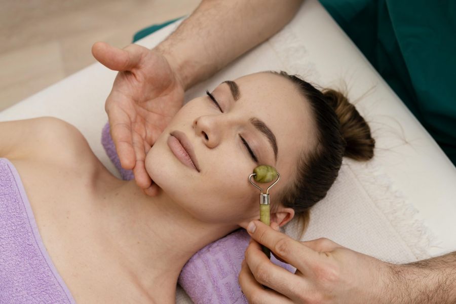 Gesichtsakupunktur Köln – TCM für strahlende Haut Therapeut verwendet Jade-Roller zur Entspannung der Gesichtsmuskulatur
